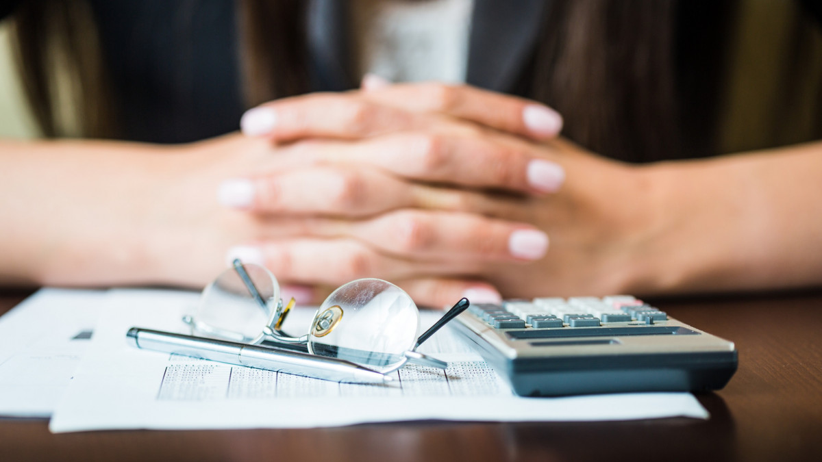 Close up of businesswomans hands with pen, glasses, and calculator doing some financial calculations