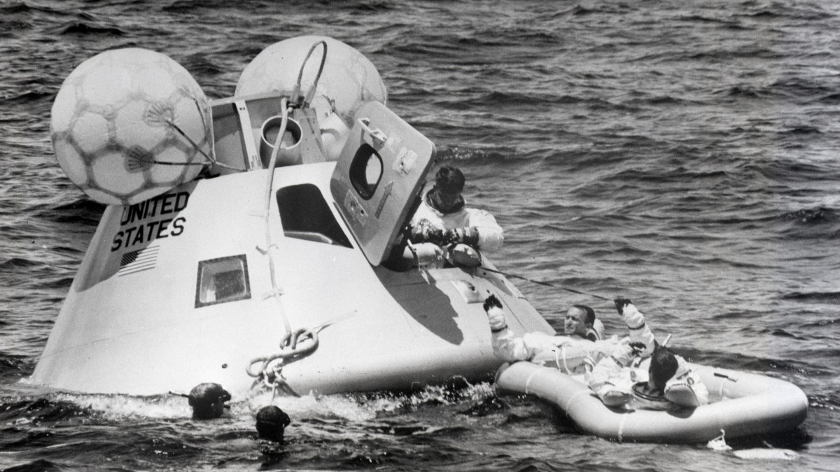 (Original Caption) 8/31/1968-: Frogmen (L) help astronauts during egress training. Walter Cunningham and Donn Eisele are shown pulling Walter Schirra out of a space capsule onto a rubber raft.