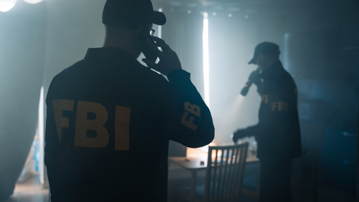 An action movie scene with two FBI agents at the crime scene in a foggy room of the criminals apartment, calling criminologists on the phone