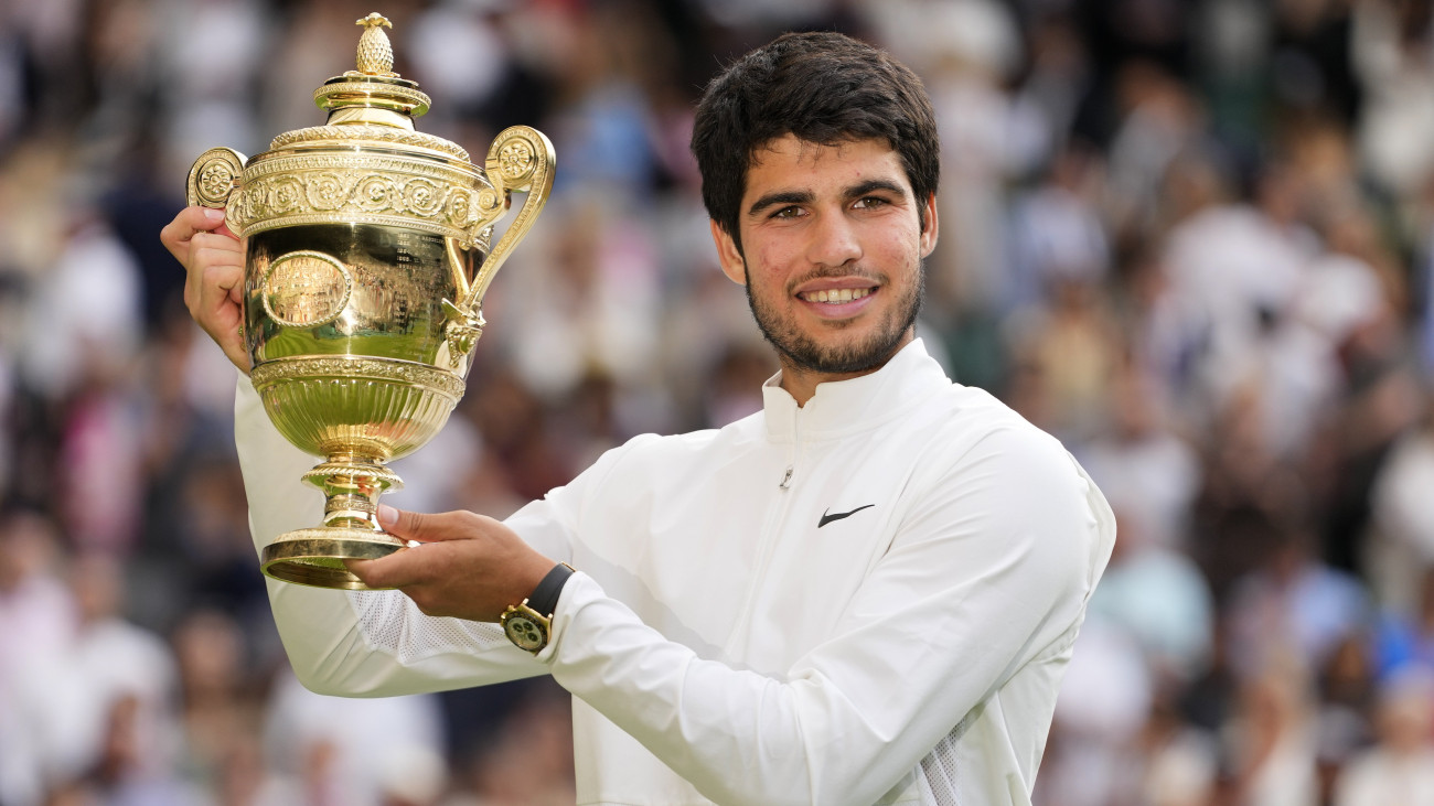 A spanyol Carlos Alcaraz a trófeával, miután győzött a szerb Novak Djokovic ellen a wimbledoni teniszbajnokság férfi egyesének döntőjében 2023. július 16-án.