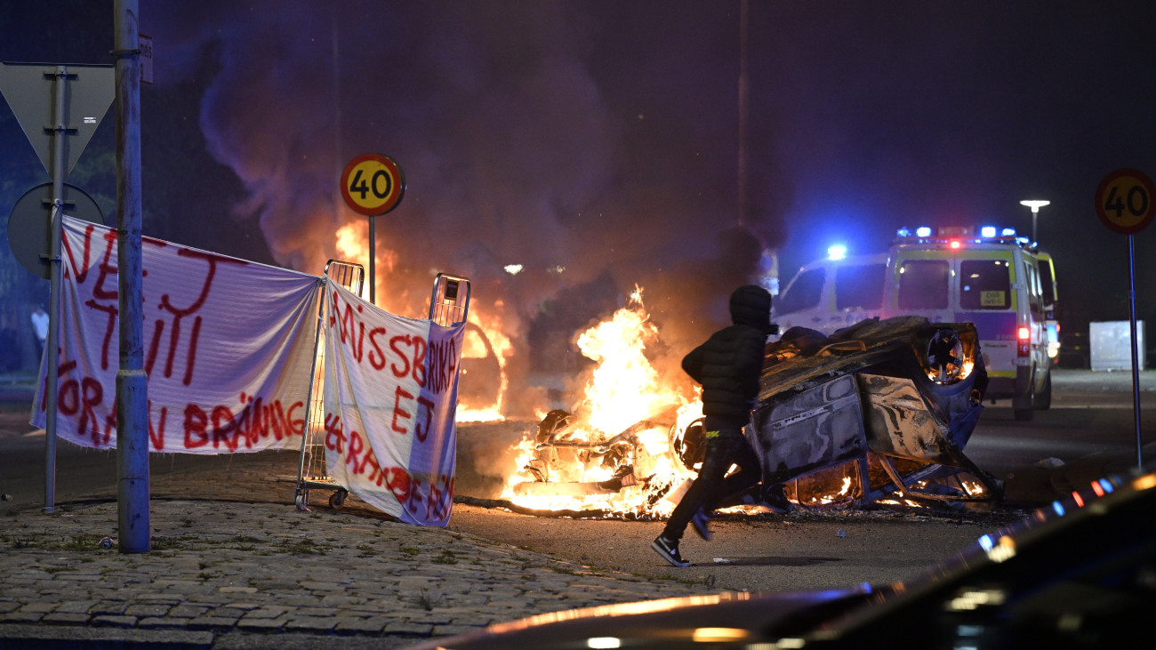 Tüntető fut egy lángoló autó előtt Malmö egyik bevándorlók lakta negyedében 2023. szeptember 4-én hajnalban. Az összecsapások azt követően törtek ki, hogy egy iszlámellenes tüntető Koránt égetett. A rendőrség több mint tíz embert vett őrizetbe.
