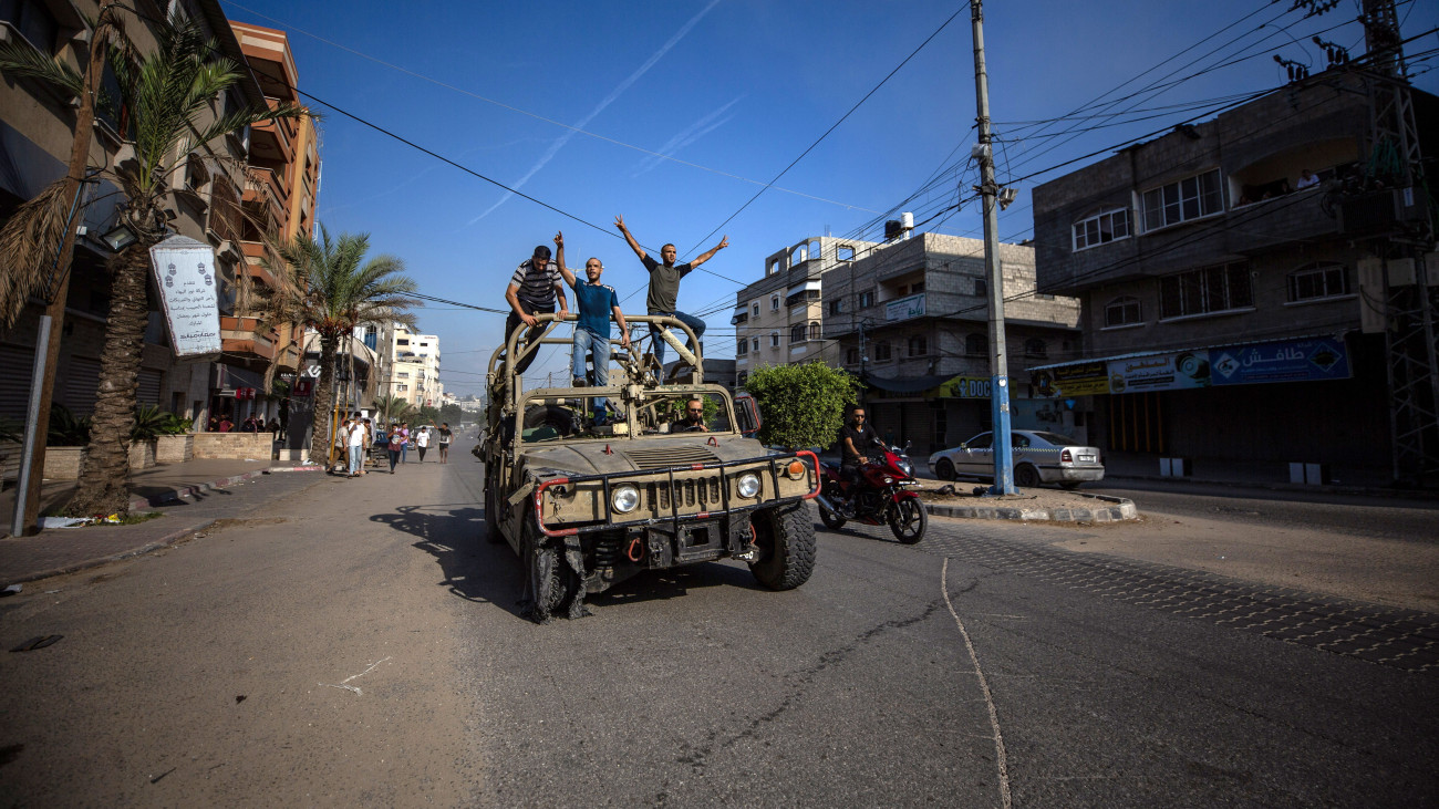 Palesztin férfiak egy izraeli katonai járművön a Gázai övezet északi részén 2023. október 7-én. A Hamász palesztin iszlamista szervezet reggel óta 2500 rakétát lőtt ki Izrael déli és középső részére a Gázai övezetből, és több tucat fegyverese hatolt be izraeli településekre. Eddig 22 halottról és félezer sebesültről tudni, a fegyveresek izraeli túszokat hurcoltak magukkal a Gázai övezetbe. Izrael teljes mozgósítást rendelt el.