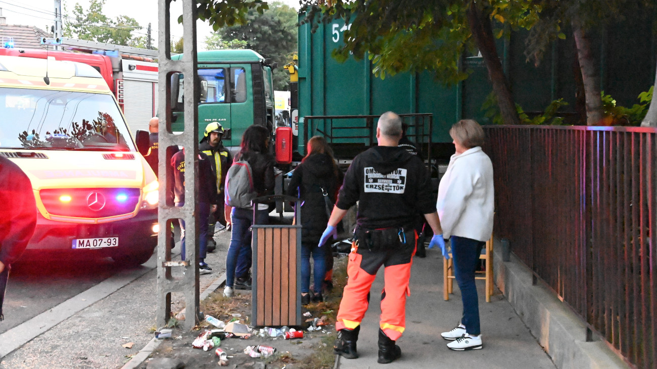 Tűzoltók és mentők egy pesterzsébeti iskolánál, ahol egy teherautó kőkerítésnek ütközött, ami rádőlt egy 9 éves gyermekre és édesanyjára 2023. október 10-én. A fiú a helyszínen életét vesztette, édesanyja lábsérülést szenvedett, őt a traumatológiai centrumba vitték.