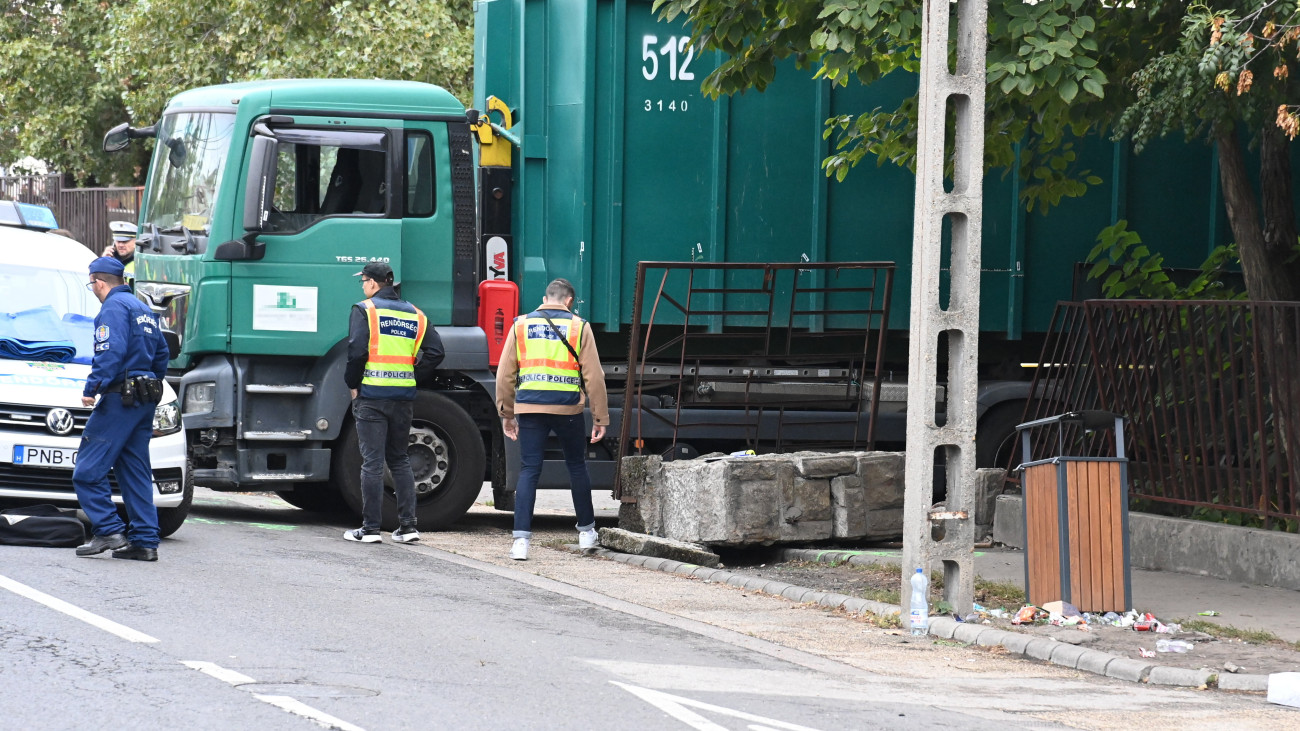 Rendőrök egy pesterzsébeti iskolánál, ahol egy teherautó kőkerítésnek ütközött, ami rádőlt egy 9 éves gyermekre és édesanyjára 2023. október 10-én. A fiú a helyszínen életét vesztette, édesanyja lábsérülést szenvedett, őt a traumatológiai centrumba vitték.