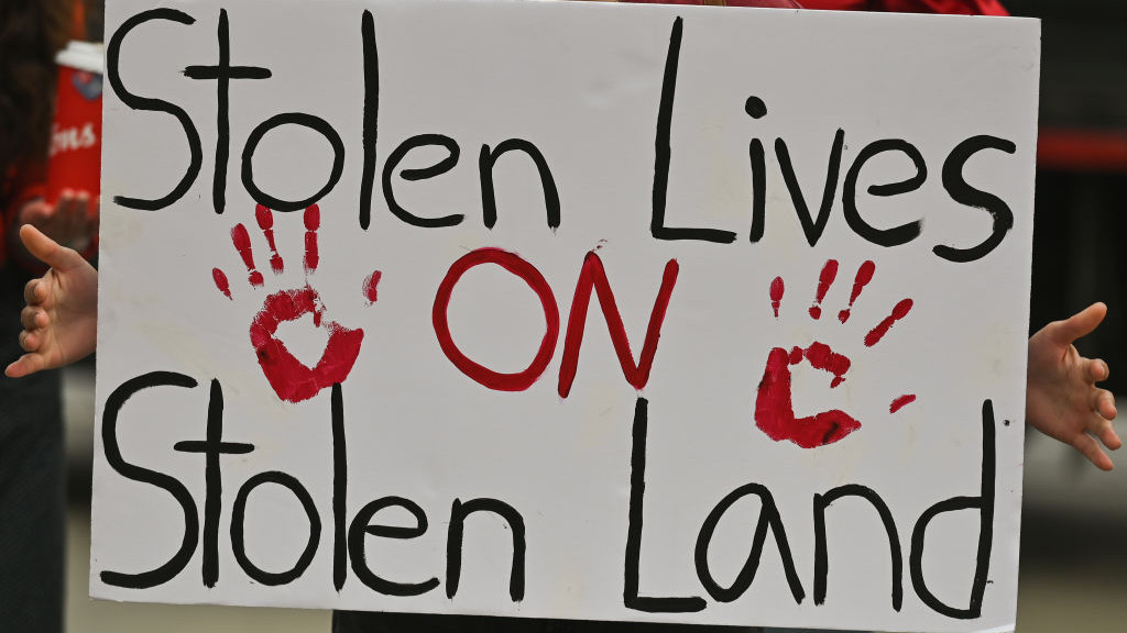 A participant holds a placard with words Stolen Lives On Stolen Land. Hundreds of women participated in the annual Red Dress Day march in downtown Edmonton, hosted by Project REDress, commemorating the lives of missing and murdered indigenous women and girls across Canada. On Thursday, 5 May 2022, in Edmonton, Alberta, Canada. (Photo by Artur Widak/NurPhoto via Getty Images)