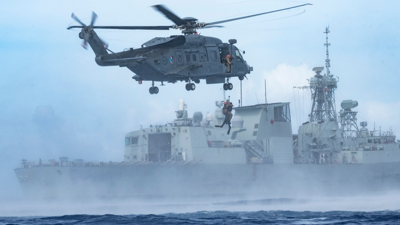 A CH-148 Cyclone helicopter flies alongside His Majestys Canadian Ship (HMCS) Vancouver while conducting wet hoist training operations during Exercise SAMA SAMA in the Philippine Sea on 11 October 2023.   Photo credit: Corporal Alisa Strelley, Canadian Armed Forces Photo.