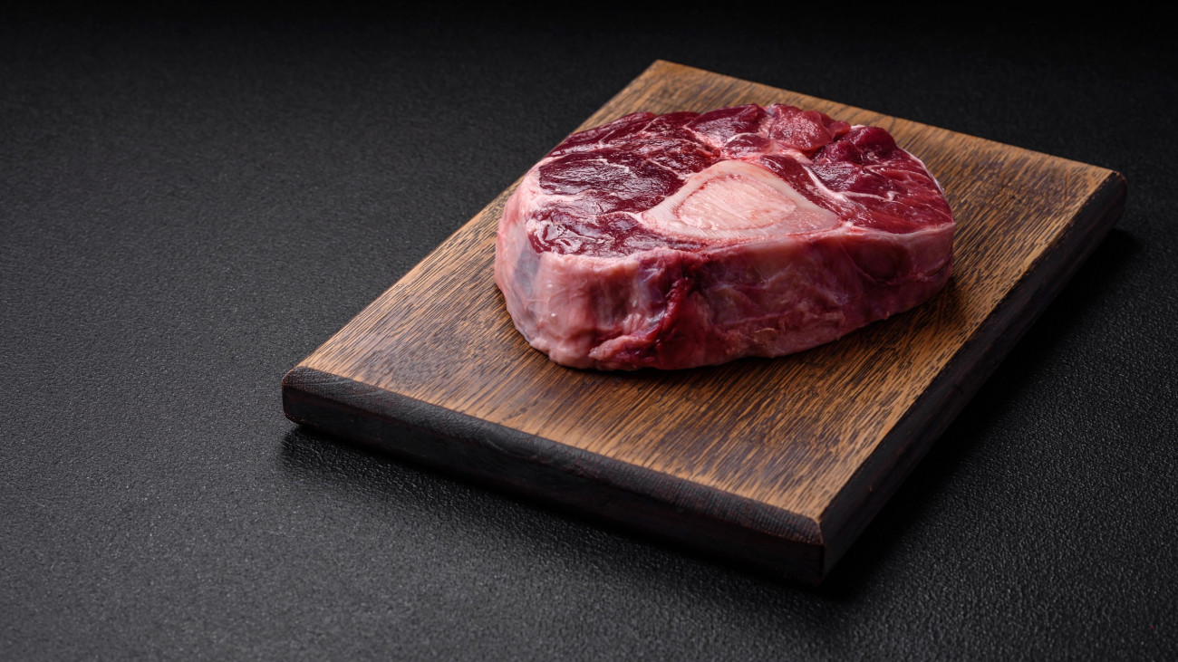 Fresh beef ossobuco steak with salt, spices and herbs on textured concrete background