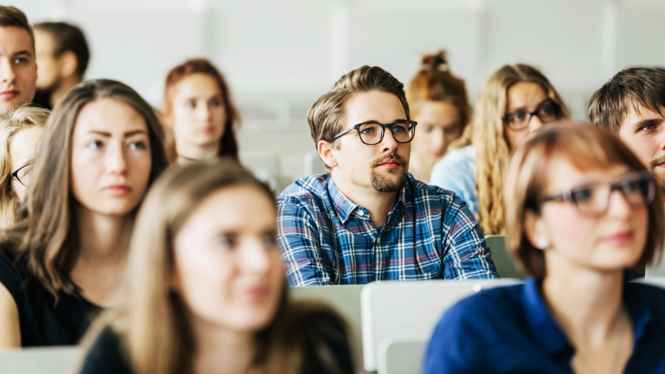 A group of young university students concentrating carefully on their professor during a lecture.