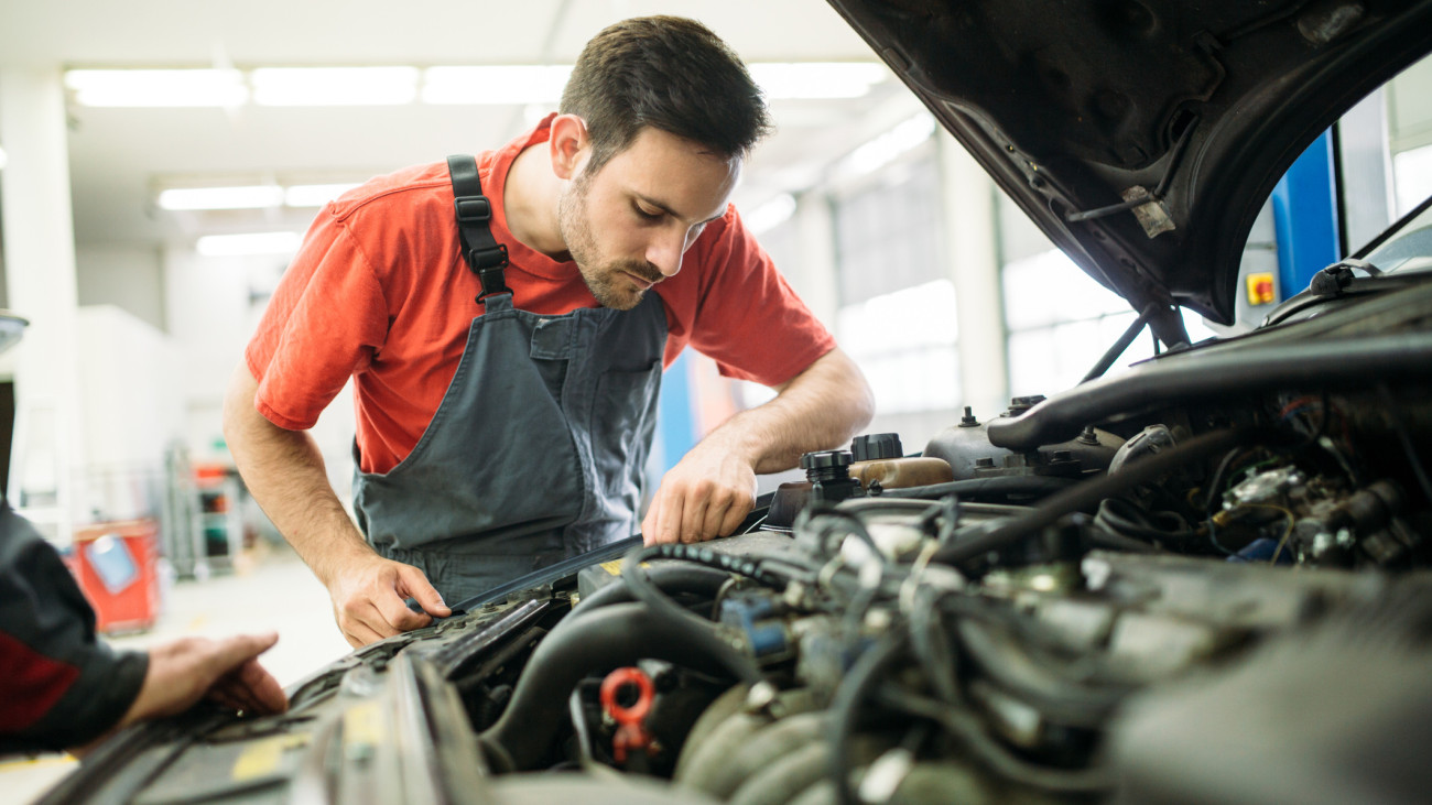 Young auto mechanic working in garage. Repair service.