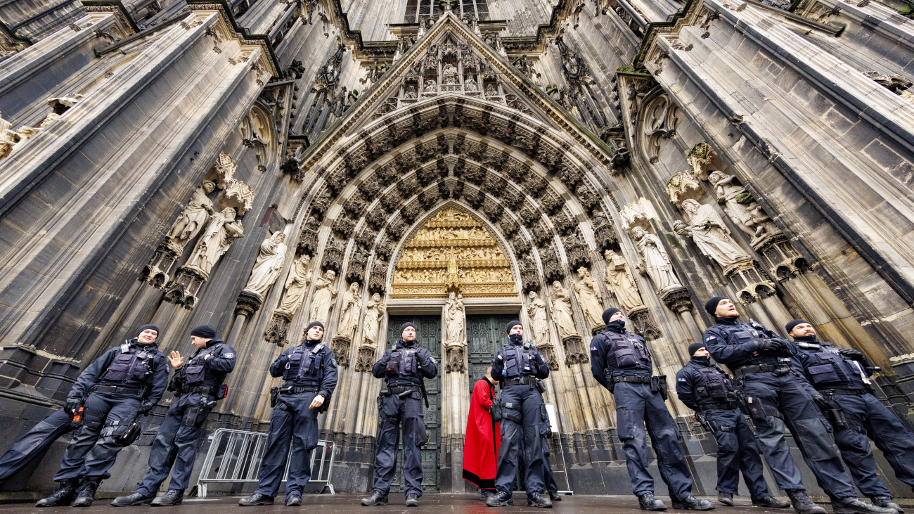 Rendőrök állnak sorfalat a kölni dóm bejárata előtt 2023. december 24-én, miután radikális iszlamista mozgalmak Európa-szerte keresztény rendezvények elleni támadásokra szólítottak fel. A német hatóságok információi szerint egy iszlamista terrorista sejt, amely az Iszlám Állam afgán ágához (ISPK) köthető, több támadást tervez Európában az ünnepi időszakban. A célpontok között lehetnek az ünnepi misék Kölnben, Madridban és Bécsben.