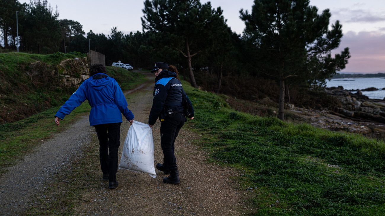 PONTEVEDRA GALICIA, SPAIN - JANUARY 04: An agent of the Local Police and a coast guard make a collection of pellets from the sand, in Illa de Arousa, on January 4, 2024, in Pontevedra, Galicia, Spain.Large quantities of plastic pellets have been appearing, since December 13 in the Rias Baixas and in the estuary of Muros e Noia in bags of about 25 kilos, with the name of a company based in Poland. This has been reported by the Noia Limpa Association, which has detailed that the loss of goods from six containers was reported near Viana do Castelo, in Portugal. The pellets are small plastic balls of less than five millimeters in size that are used to manufacture plastic products, because of their small size and light weight, it is almost impossible to clean them up once they are scattered on the beaches. (Photo By Elena Fernandez/Europa Press via Getty Images)