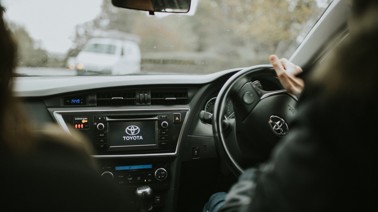 Hayward Heaths, England - October 27th, 2018: Detail of Toyota Auris car dashboard being driven by young man with the hand on the steering wheel, with daylight, with right-hand position.