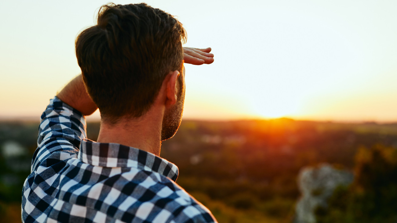 Man standing on meadow in mountains and admiring sunset