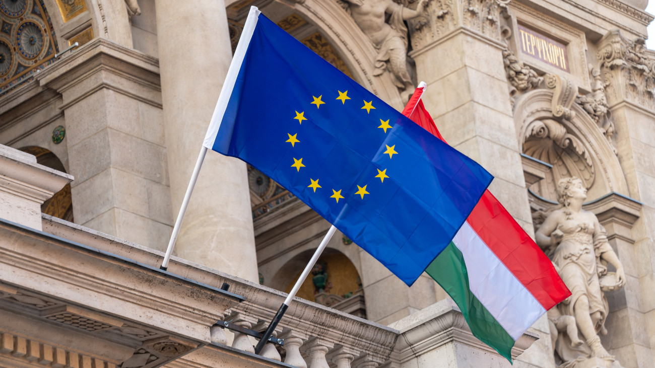 Flags of the European Union and Hungary flying from poles outside an ornate building in the centre of Hungarian capital city of Budapest