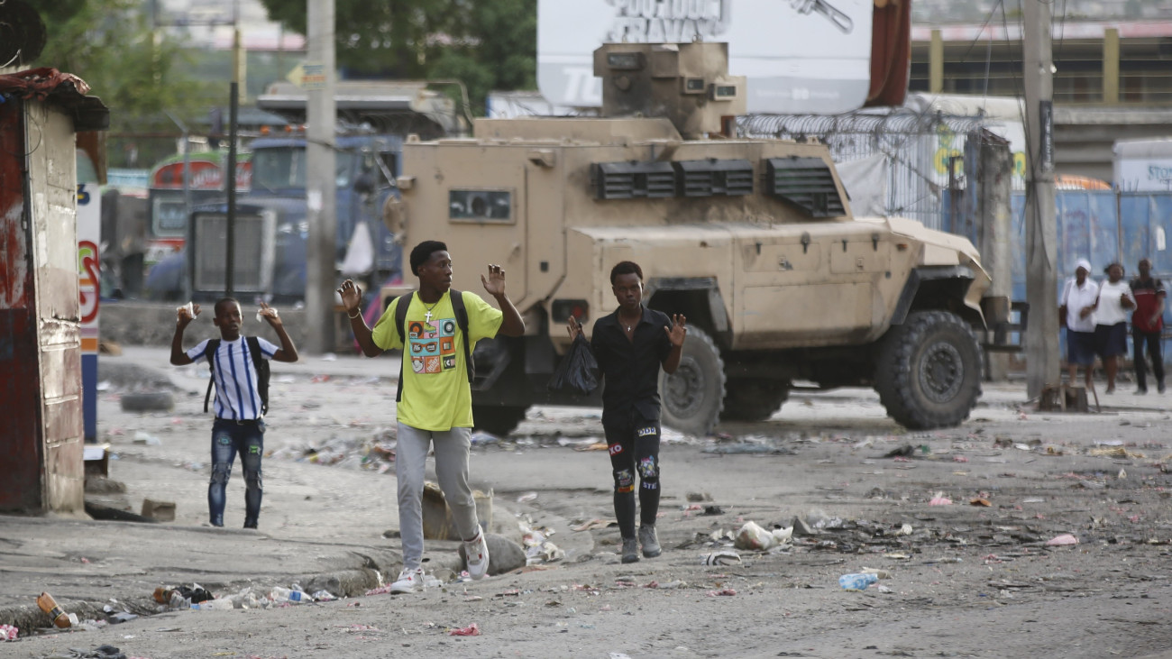 Fiatalok feltartott kézzel mennek az utcán a rendőrök és bandatagok összecsapásai idején a haiti főváros, Port-au-Prince Portail negyedében 2024. február 29-én. Az erőszakcselekmények február elején felerősödtek a súlyos válságba süllyedt karibi államban, amelynek fővárosában tíz nap alatt csaknem újabb tízezren menekültek el otthonukból.