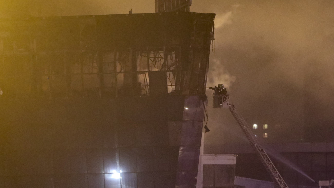 Tűzoltók fékezik meg a lángokat a Crocus City Hall nevű hangversenyteremnek otthont adó épületnél Krasznogorszkban 2024. március 22-én. Szemtanúk szerint az automata fegyverrel felszerelkezett támadók gránátot vagy gyújtóbombát dobtak a nézőtérre, ahol nagy robbanás hallatszott, majd tűz keletkezett. A támadásnak legkevesebb negyven halálos és több mint száz sebesült áldozata van.