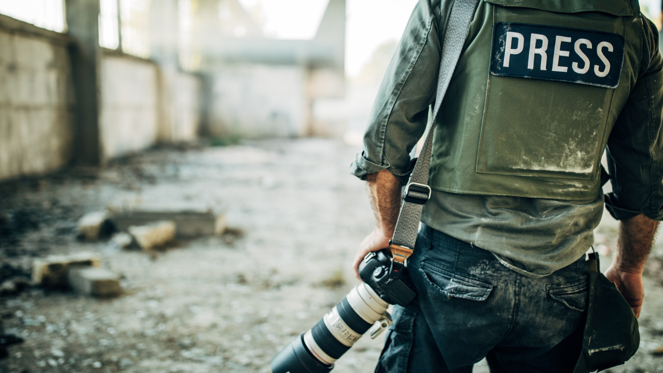 One man, war journalist with digital camera at the place of action, in war zone.