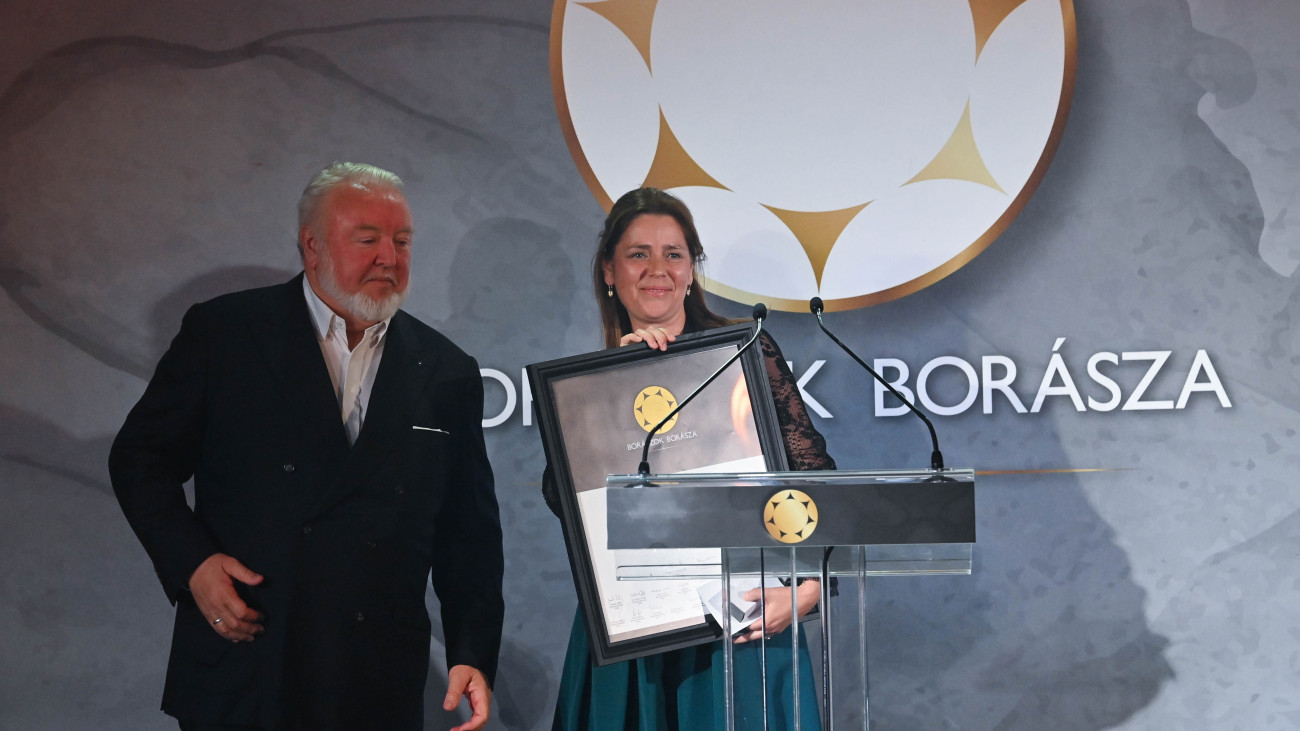 Budapest, 2024. április 27.Bárdos Sarolta, a tokaji borvidék borásza, miután átvette a Borászok Borásza díjat annak előző kitüntetettjétől, Heimann Zoltán szekszárdi borásztól (b) a budapesti New York Palotában rendezett díjátadón 2024. április 27-én.