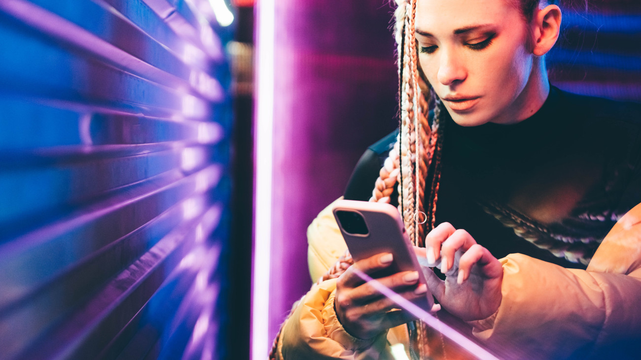 Woman using mobile phone in neon lights.