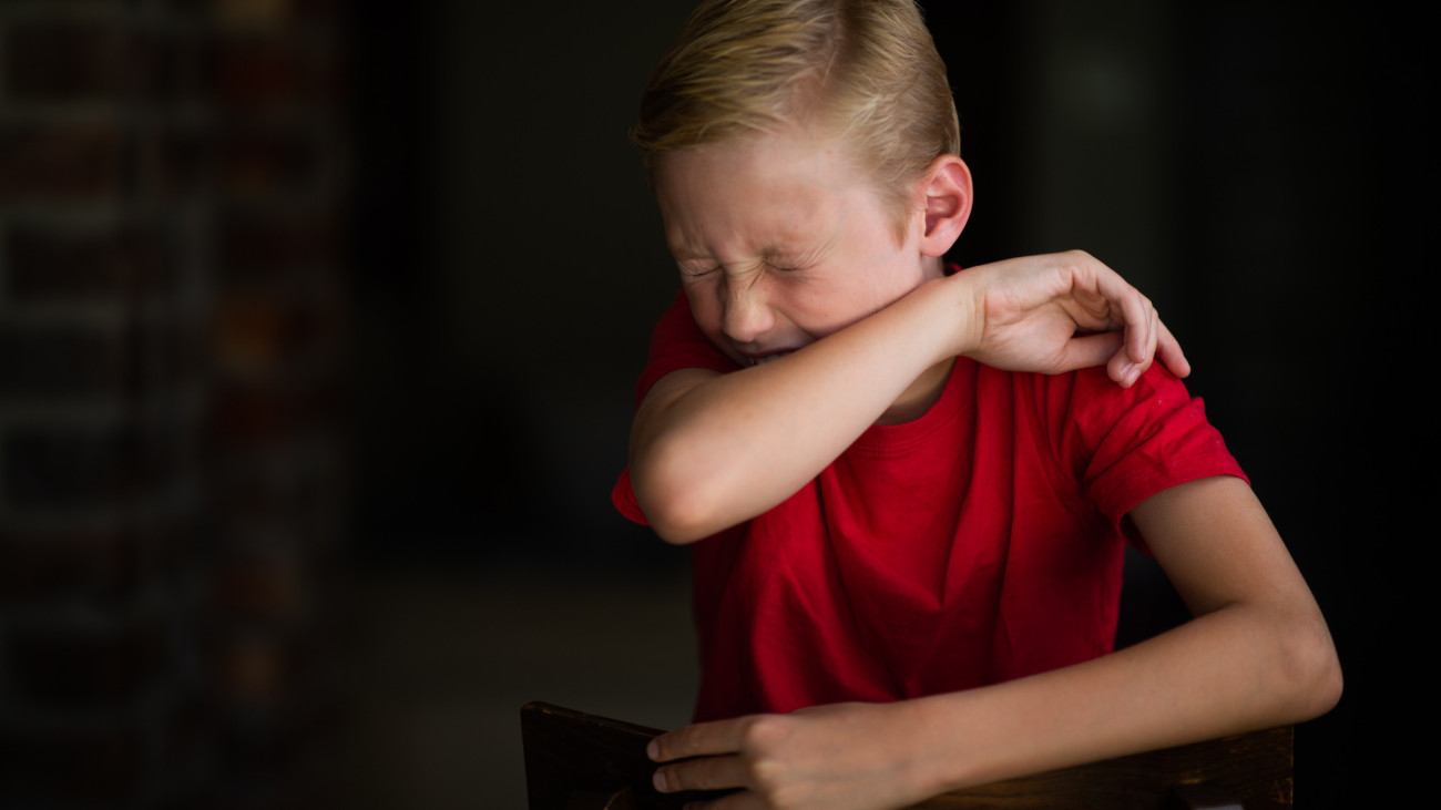 köhögés tüsszögés  A young 11-year old blond Caucasian boy demonstrating the correct way to cough and sneeze into an elbow rather than using hands to stop the spreading of the Coronavirus during lockdown in South Africa due to the COVID-19.