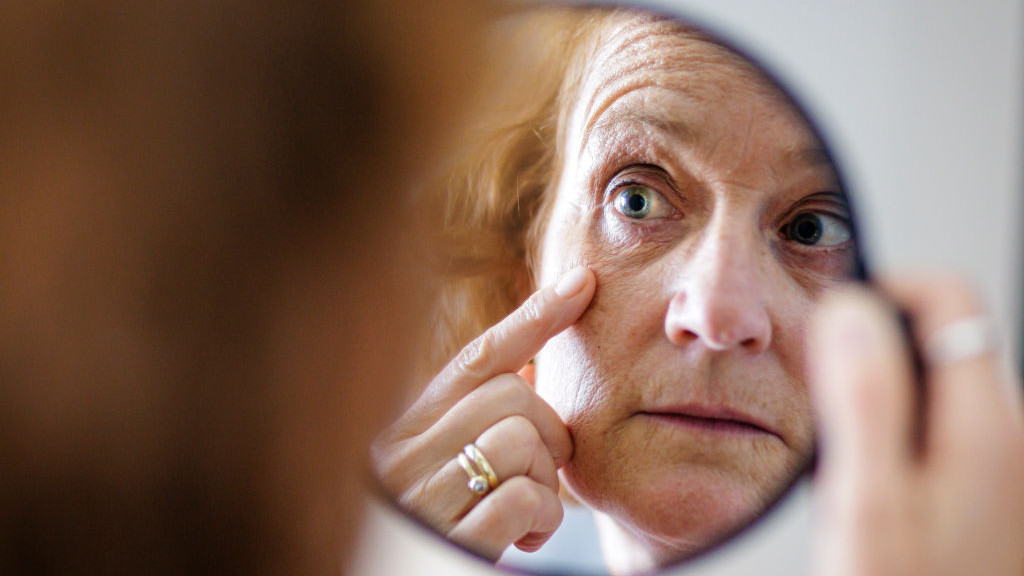 BERLIN, GERMANY - AUGUST 13: Symbolic photo on the topic of eye wrinkles. A woman looks at her eye wrinkles in the mirror on August 13, 2024 in Berlin, Germany. (Photo Illustration by Thomas Trutschel/Photothek via Getty Images)