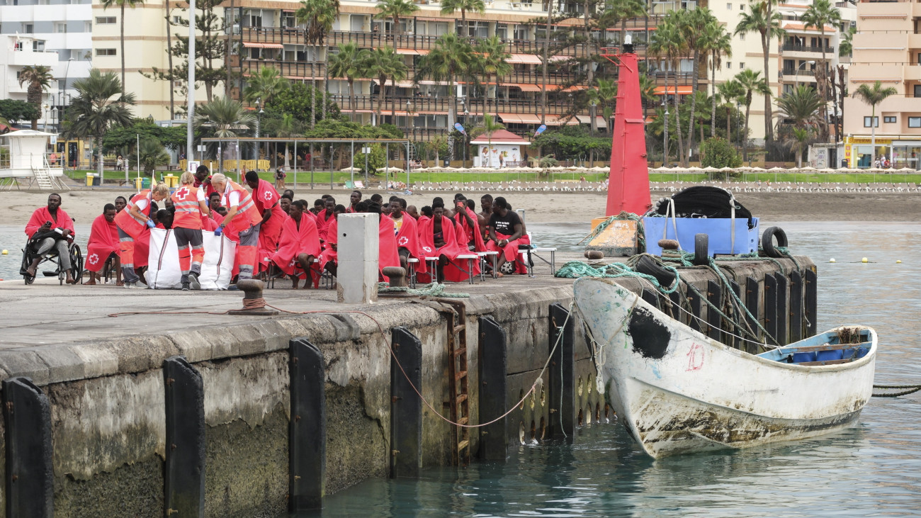 Afrikai illegális bevándorlókat látnak el a Spanyol Vöröskereszt munkatársai a kanári-szigeteki Tenerifén fekvő Los Cristianos kikötőjében 2024. október 17-én, miután a spanyol tengeri mentőszolgálat hajója 58 migránssal a fedélzeten kikötött a szigeten. A Nemzetközi Migrációs Szervezet (IOM) adatai szerint Spanyolországban mintegy 8700 migránst regisztráltak a 2024. április és június közötti negyedévben.