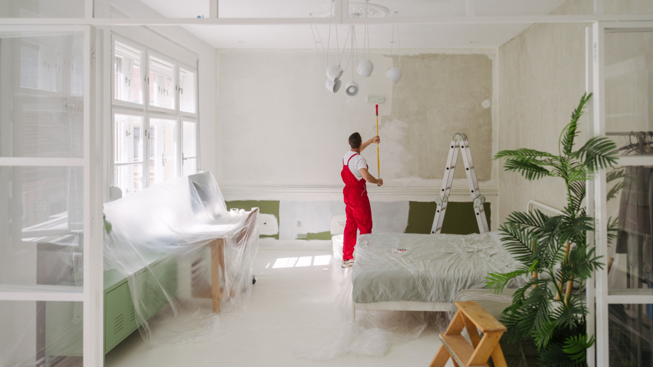 Photo of a professional house painter painting walls in the apartment