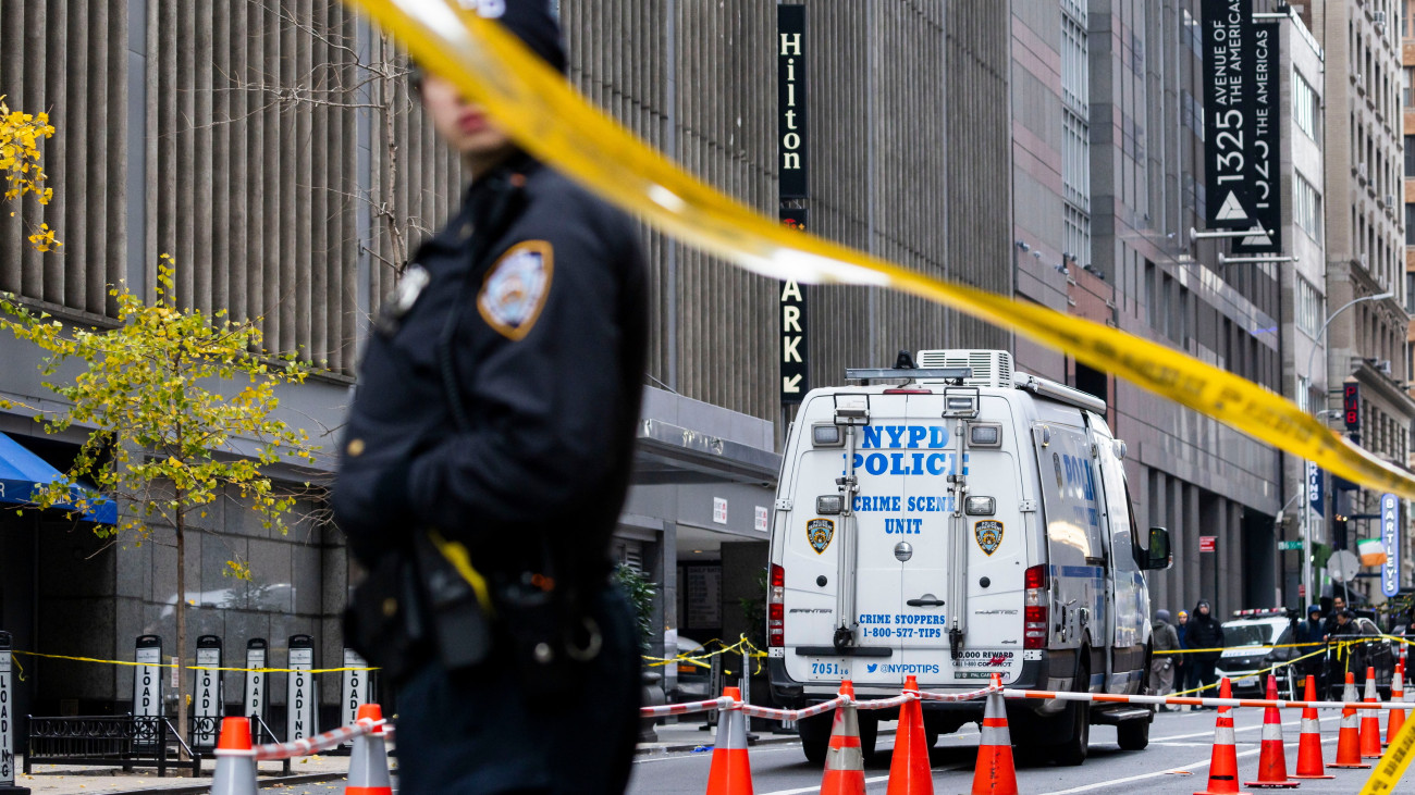 helyszínt biztosító rendőr a New York-i Hilton Szálloda előtt 2024. december 4-én, miután a nagyváros Manhattan negyedében lőfegyverrel meggyilkolták Brian Thompsont, a UnitedHealthcare amerikai egészségbiztosító társaság vezérigazgatóját. A tettes egyelőre szökésben van.