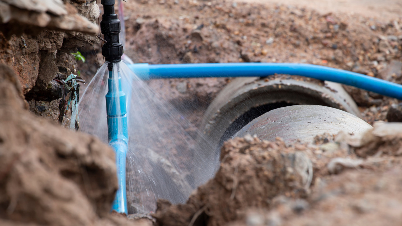 Water pipe break .Exposing a burst water main, focused on the spraying water and the pipe.