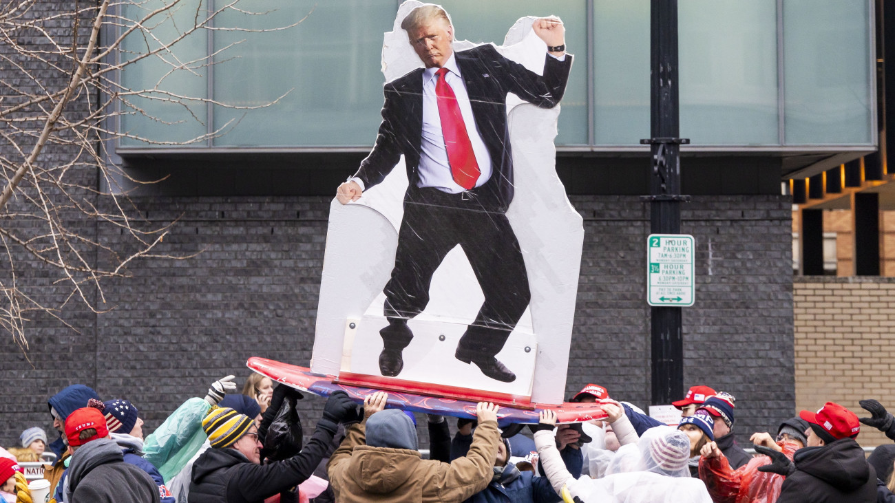 Donald Trump megválasztott amerikai elnököt táncolva ábrázoló képet fognak támogatói, miközben sorban állnak a washingtoni Capital One Arénában a beiktatásának előestéjén, 2025. január 19-én tartott nagygyűlésre.