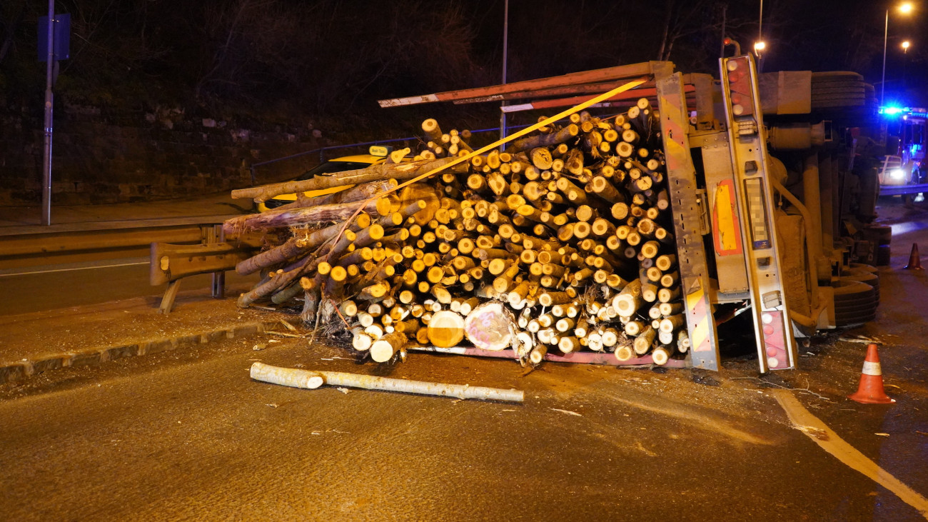 Oldalára borult, fát szállító teherautó a Hegyalja úton, a Krisztina körút közelében 2025. március 3-án.
