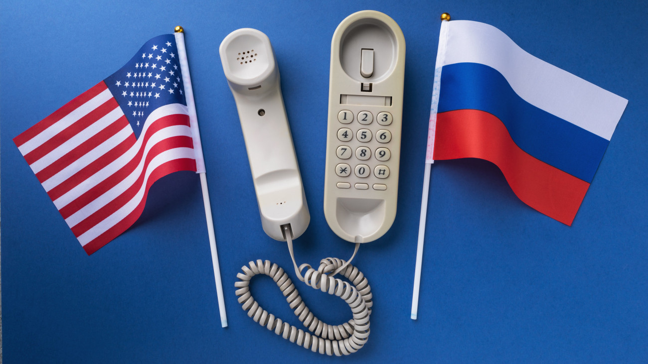 Old telephone and two flags on a blue background, a concept on the theme of telephone conversations between the USA and Russia