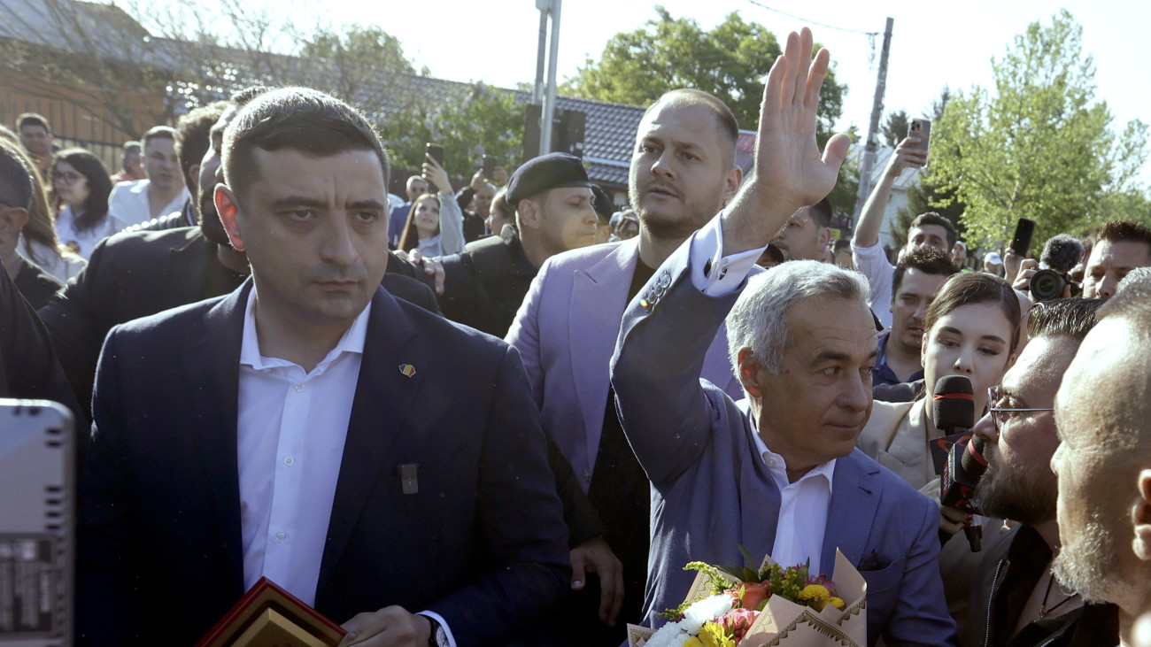 Az eredeti választás érvénytelenített első fordulójában győztes, majd a jelöltségtől eltiltott Calin Georgescu (j) George Simion, a többi parlamenti párt által szélsőségesnek tartott Románok Egyesüléséért Szövetség (AUR) elnöke és jelöltje társaságában távozik egy szavazóhelyiségből, miután szavazott a megismételt romániai elnökválasztás első fordulójában a Bukarest közelében fekvő Mogosoaiában 2025. május 4-én.