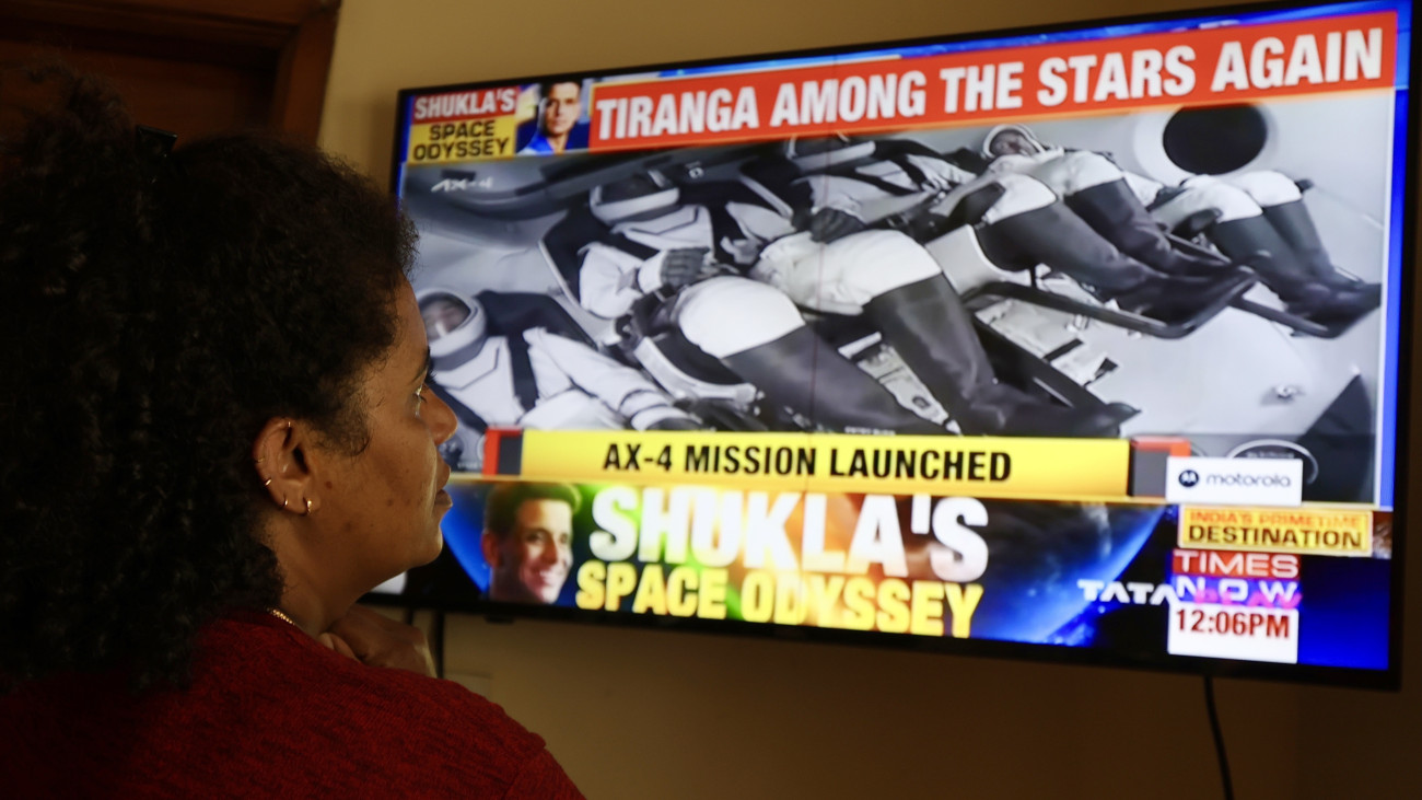 Egy indiai nő Bengaluruban televízión nézi, amint felbocsátják a SpaceX amerikai űrkutatási magánvállalat Falcon 9-es rakétájával összekapcsolt Crew Dragon személyszállító űrhajót a floridai Kennedy Űrközpontból 2025. június 25-én. Az űrhajóval az Axiom 4 (Ax-4) legénysége: Kapu Tibor magyar űrhajós, valamint a lengyel Slawosz Uznanski-Wisniewski, az indiai Subhansu Sukla és az amerikai Peggy Whitson utazik a Föld körül keringő Nemzetközi Űrállomásra (ISS). Az űrhajó várhatóan június 26-án kapcsolódik az űrállomáshoz, ahol a legénység a tervek szerint 14 napot tölt majd.