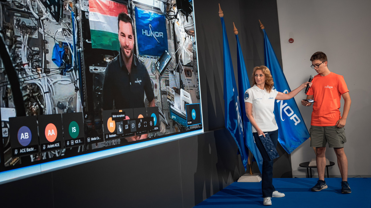 A HUNOR-program által közreadott képen az Országos Középiskolai Tanulmányi Verseny (OKTV) egyik győztes középiskolás diákja kérdést tesz fel élő beszélgetésben Kapu Tibornak, a Nemzetközi Űrállomáson (ISS) tartózkodó űrhajósnak Ferencz Orsolya űrkutatásért felelős miniszteri biztos, az esemény moderátorának társaságában a HUNIVERZUM Látogatóközpontban, a Millenárison 2025. július 2-án.