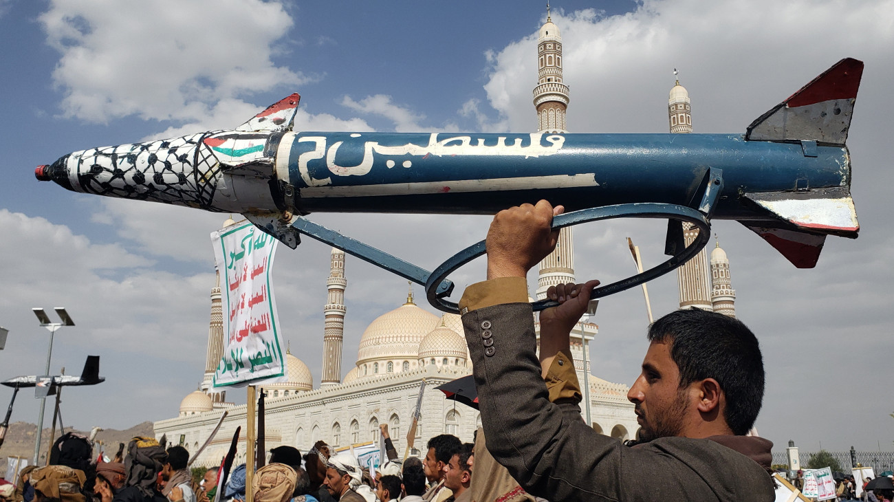 A Gázai övezetben élő palesztinokat támogató jemeni húszi lázadók támogatóinak egyike álrakétát emel a magasba az Egyesült Államok és Izrael elleni tüntetésen Szanaában 2025. június 27-én. A húszik rendszeresen hajtanak végre rakéta- és dróntámadásokat a Vörös-tengeren és az Ádeni-öbölben közlekedő kereskedelmi hajók, valamint brit és amerikai hadihajók ellen 2023 novembere óta, megtorlásul Izrael gázai és libanoni hadműveletei miatt.