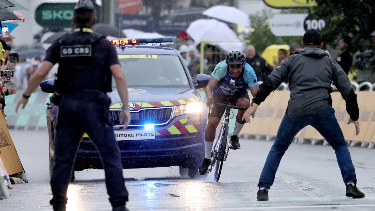A pályára behatoló biciklist készülnek megállítani biztonsági emberek a Tour de France francia országúti kerékpáros körverseny 17., Bollene és Valence közötti 160,4 kilométeres szakaszának célvonala előtt 2025. július 23-án.