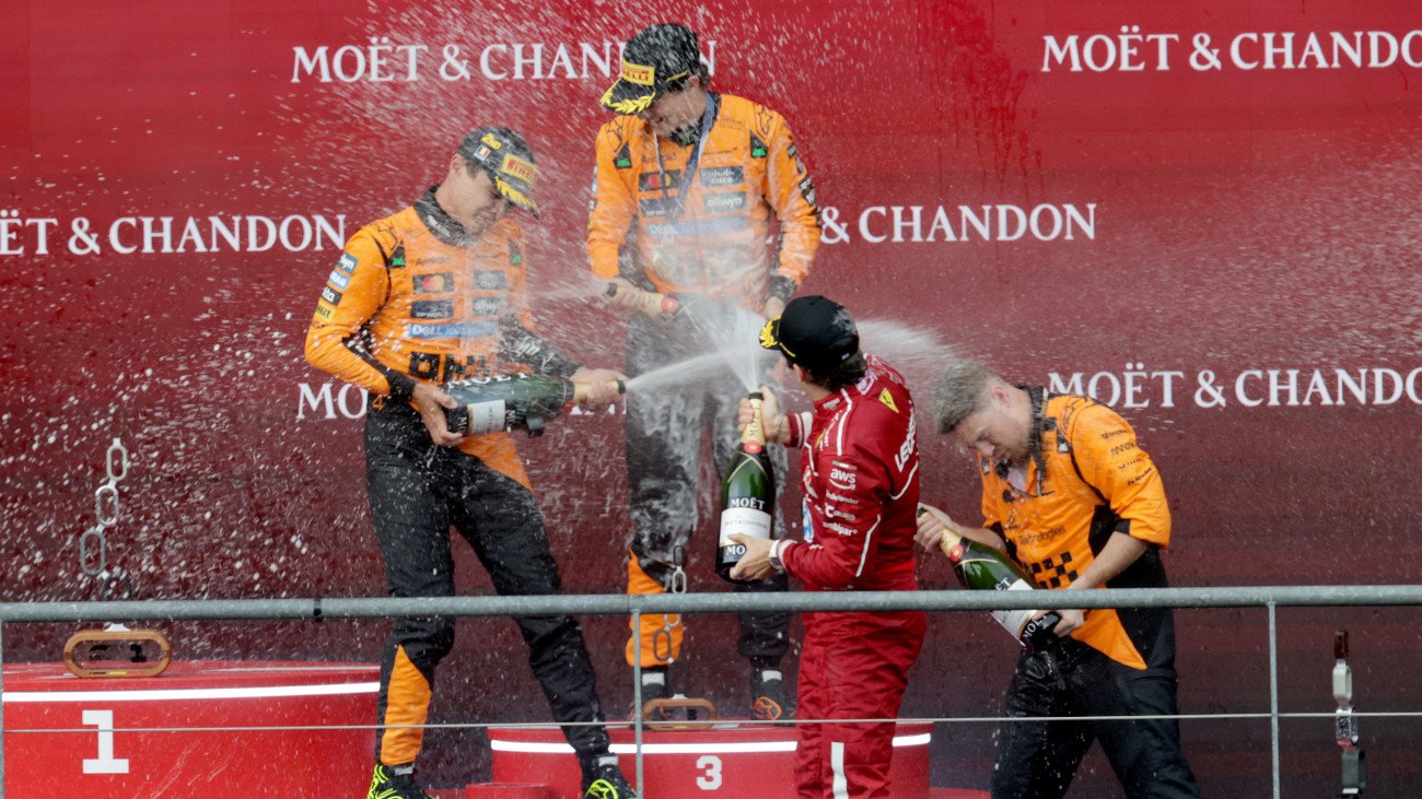 A második helyezett Lando Norris, a McLaren brit versenyzője (b), győztes ausztrál csapattársa, Oscar Piastri (b2) és a harmadik helyezett Charles Leclerc, a Ferrari monacói versenyzője (j2) pezsgővel ünnepel a Forma-1-es autós gyorsasági világbajnokság Belga Nagydíjának eredményhirdetésén a spa-francorchampsi pályán 2025. július 27-én.
