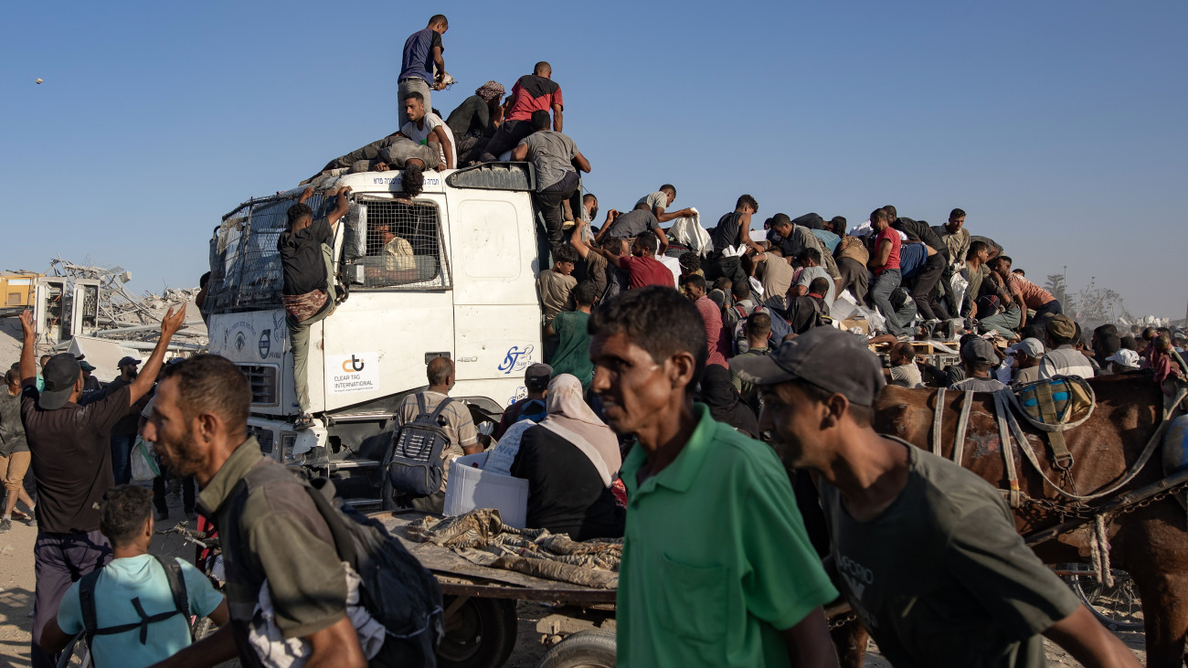 A Morag folyosón élelmet és más humanitárius segélyt szállító teherautóra kapaszkodnak fel palesztinok a Gázai övezet féli részén fekvő Hán-Júnisz környékén 2025. augusztus 4-én.