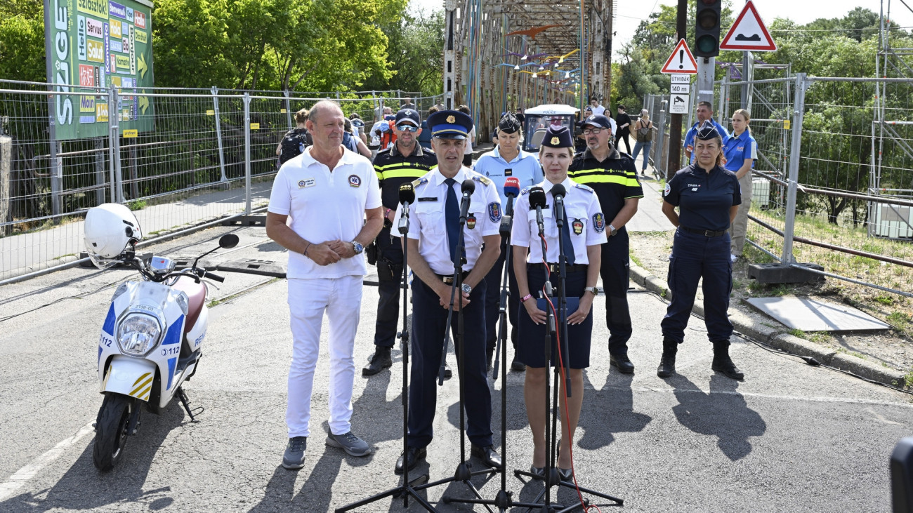 Csécsi Soma, a Budapesti Rendőr-főkapitányság (BRFK) szóvivője (k),  Herceg Erika Evelin rendőr százados (j), és Győrfi Pál, az Országos Mentőszolgálat szóvivője (b) a 31. Sziget fesztivál nyitónapján tartott sajtótájékoztatón, a Hajógyári-szigetre vezető K hídnál 2025. augusztus 6-án. Francia, német és holland rendőrök segítik a Budapesti Rendőr-főkapitányság az idei Sziget fesztiválon. Az Országos Mentőszolgálat egy ellátóközponttal és kilenc mentőegységgel van jelen a rendezvényen. Mögöttük holland és francia rendőrök.
