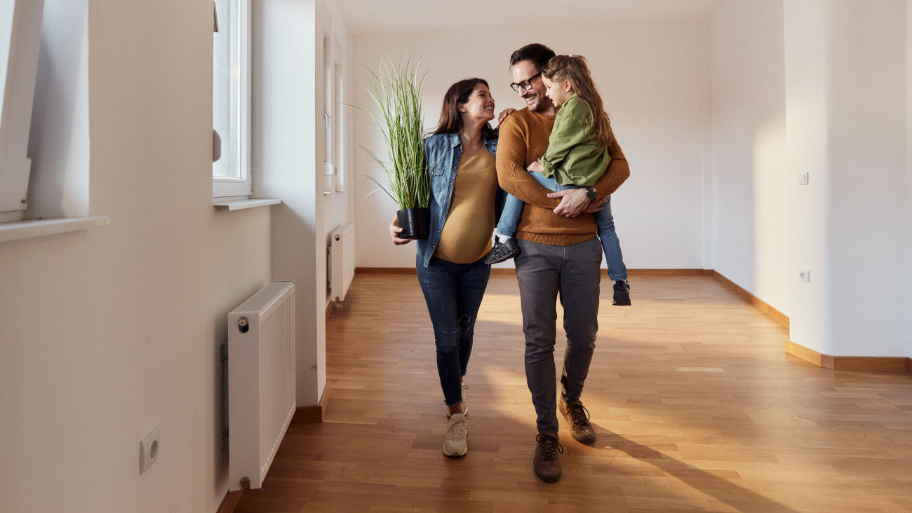 Happy expecting family talking while carrying their belongings in an empty apartment. Copy space.