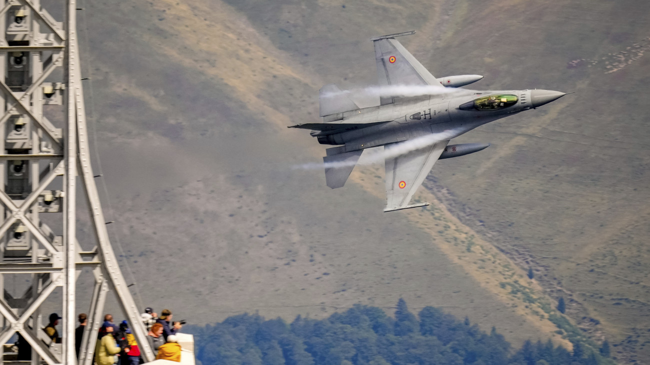 Román F-16-os vadászbombázó repülőgépet néznek érdeklődők a Hősök keresztje emlékműnél a román és a német légierő akrobatikus bemutatóval egybekötött gyakorlatozásán az erdélyi Bucsecs-hegységben levő Caraiman-csúcson, Busteni város térségében 2025. augusztus 26-án.
