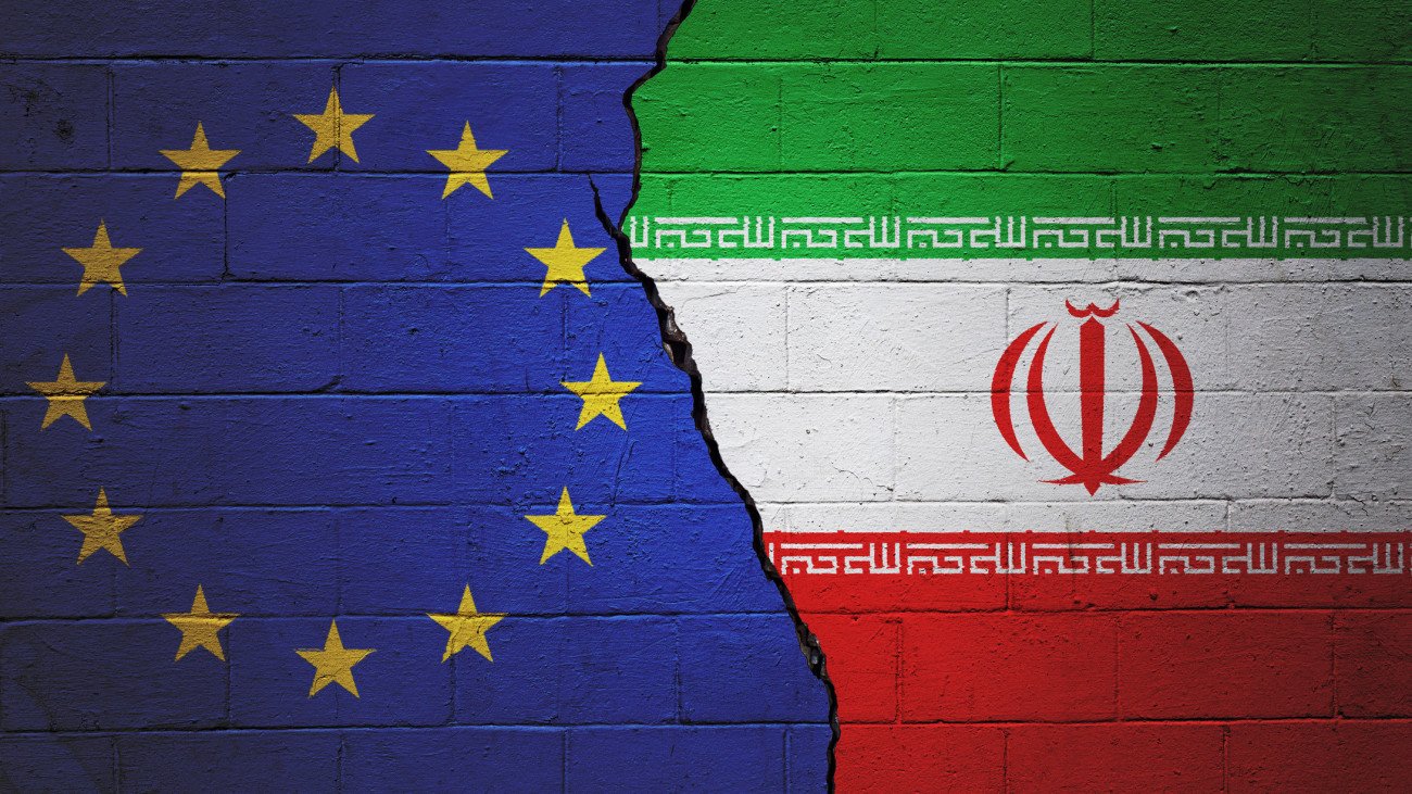 Cracked brick wall painted with a European Union flag on the left and a Iranian flag on the right.