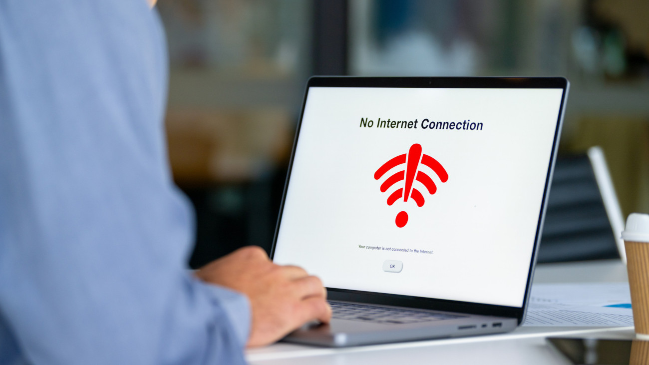 Close up of Businessman in the office frustrated with a no internet connection warning sign. The warning sign is a wifi icon with and exclamation sign