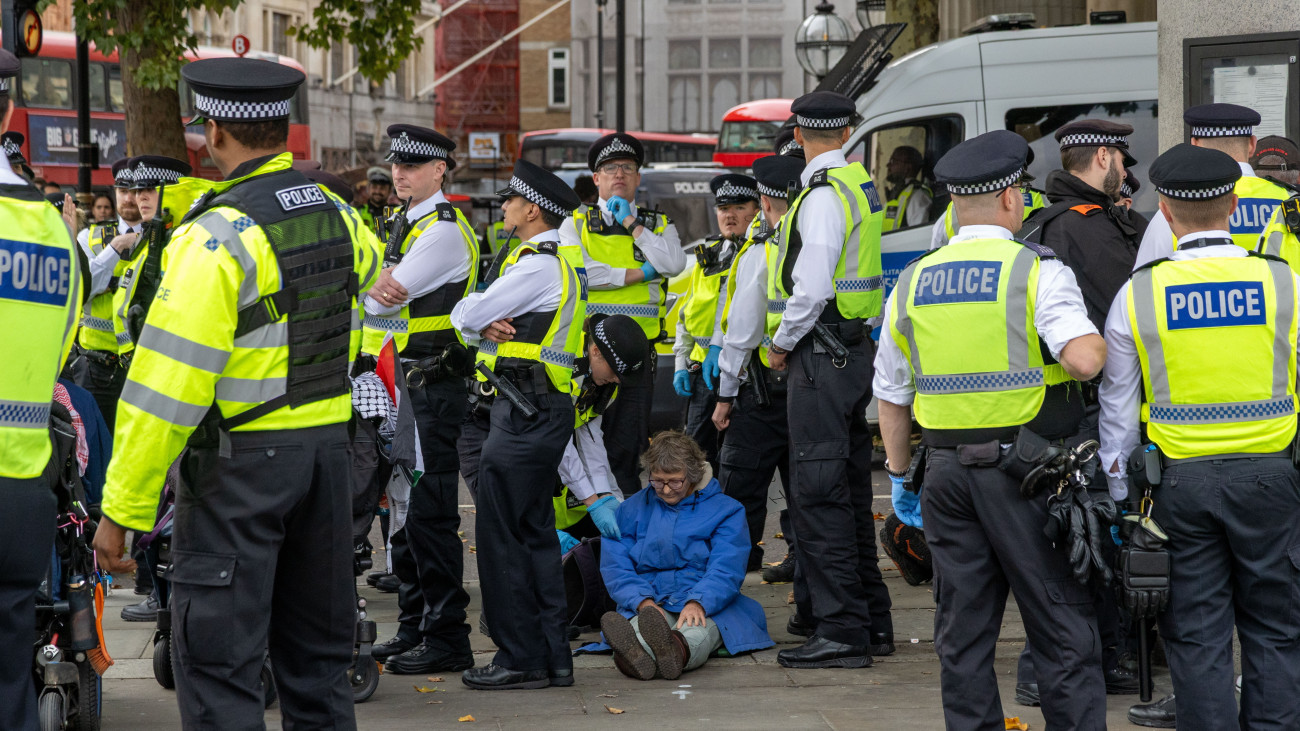 Rendőrök őrizetbe vesznek egy palesztinbarát tüntetőt az Izrael gázai övezeti hadművelete ellen és a brit kormány által terrorszervezetnek nyilvánított és betiltott Palestine Action nevű szerveződés mellett tartott tiltakozóakción Londonban 2025. október 4-én.
