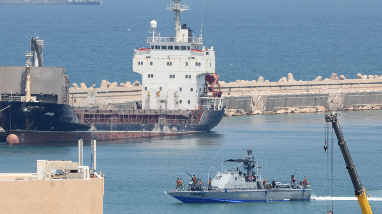 Az izraeli haditengerészet hajója egy teherhajó előtt, a dél-izraeli Asdód kikötőjében 2025. június 9-én. Izraeli haditengerészek elfogták a palesztinoknak szánt segélyt kísérő palesztinpárti aktivistákat, köztük Greta Thunberg svéd klímaaktivistát szállító és Gázába tartó Madleen nevű hajót Asdód közelében.