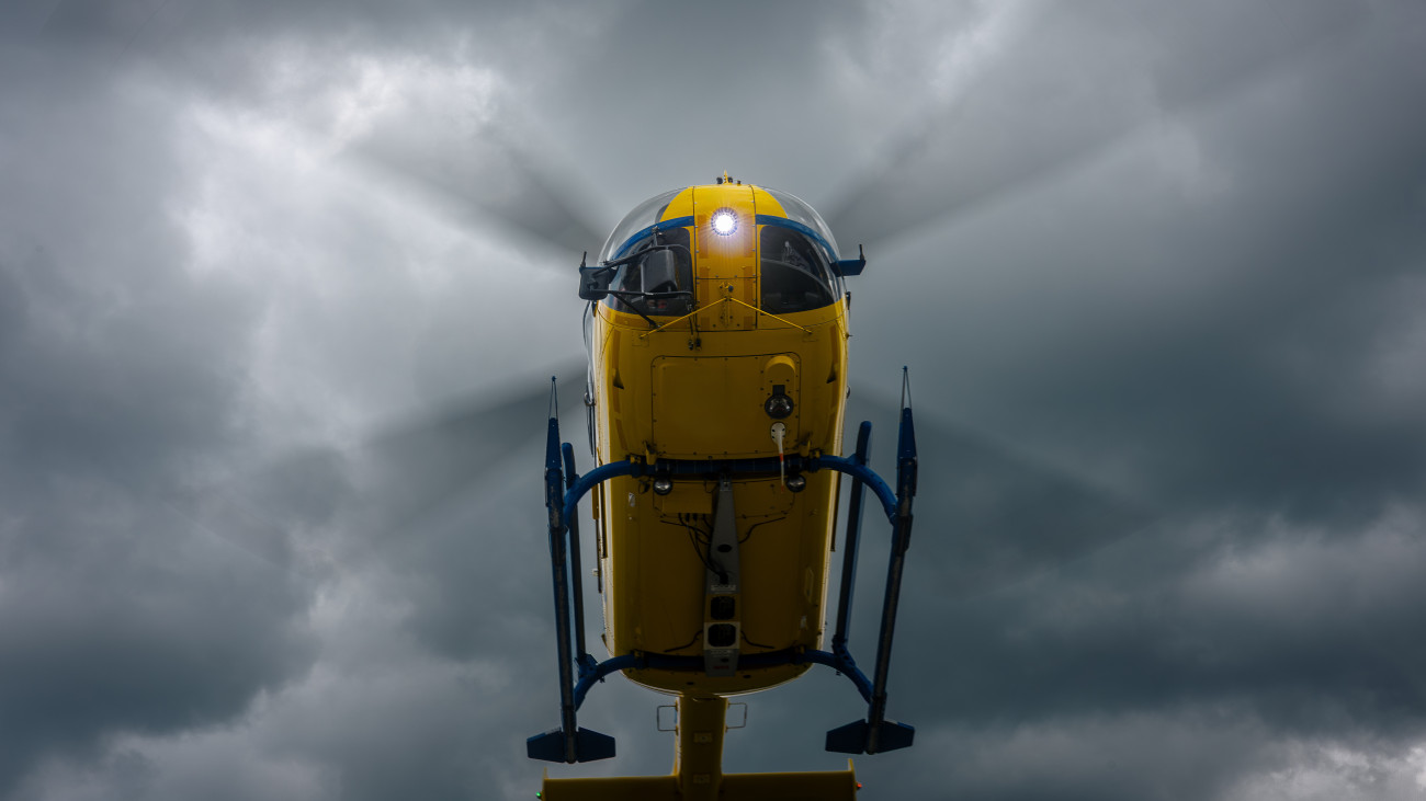 Low angle view on flying yellow helicopter emergency medical service against dramatic sky.