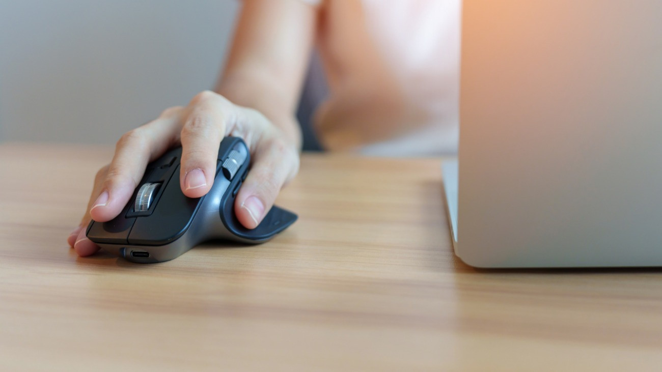 woman hand using ergonomic vertical mouse during working on Adjustable desk, prevention wrist pain. De Quervain s tenosynovitis, Intersection Symptom, Carpal Tunnel or Office syndrome concept