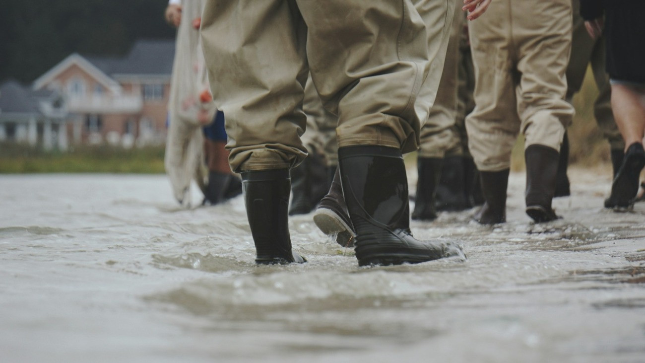 Árvízi elhárításban résztvevő gumicsizmás, védőruhás emberek