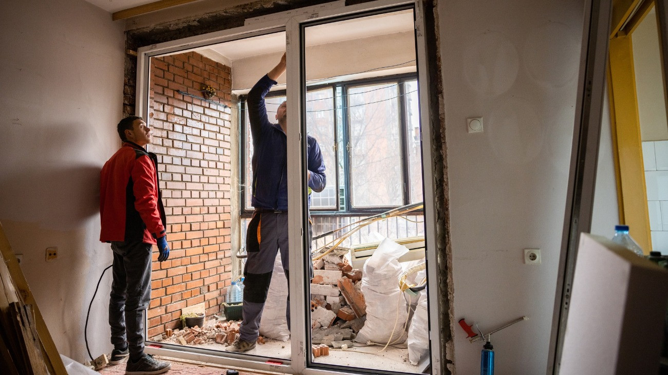 Two male workers are installing PVC window in the apartment.